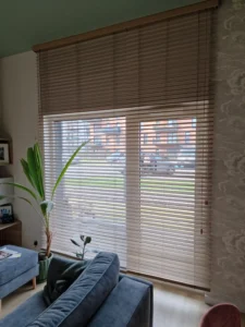 Szerokie, jasne żaluzje bambusowe w przytulnym salonie, doskonale kontrolujące wpadające światło. Elegancka osłona okienna wykonana na wymiar w Poznaniu.
